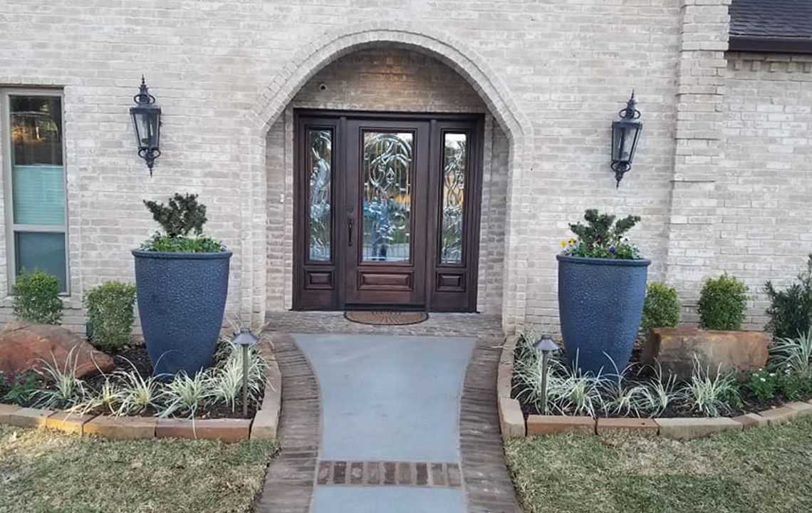 front of a house with two large flower pots and landscaping