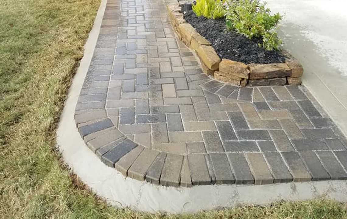 a brick walkway with a flower bed